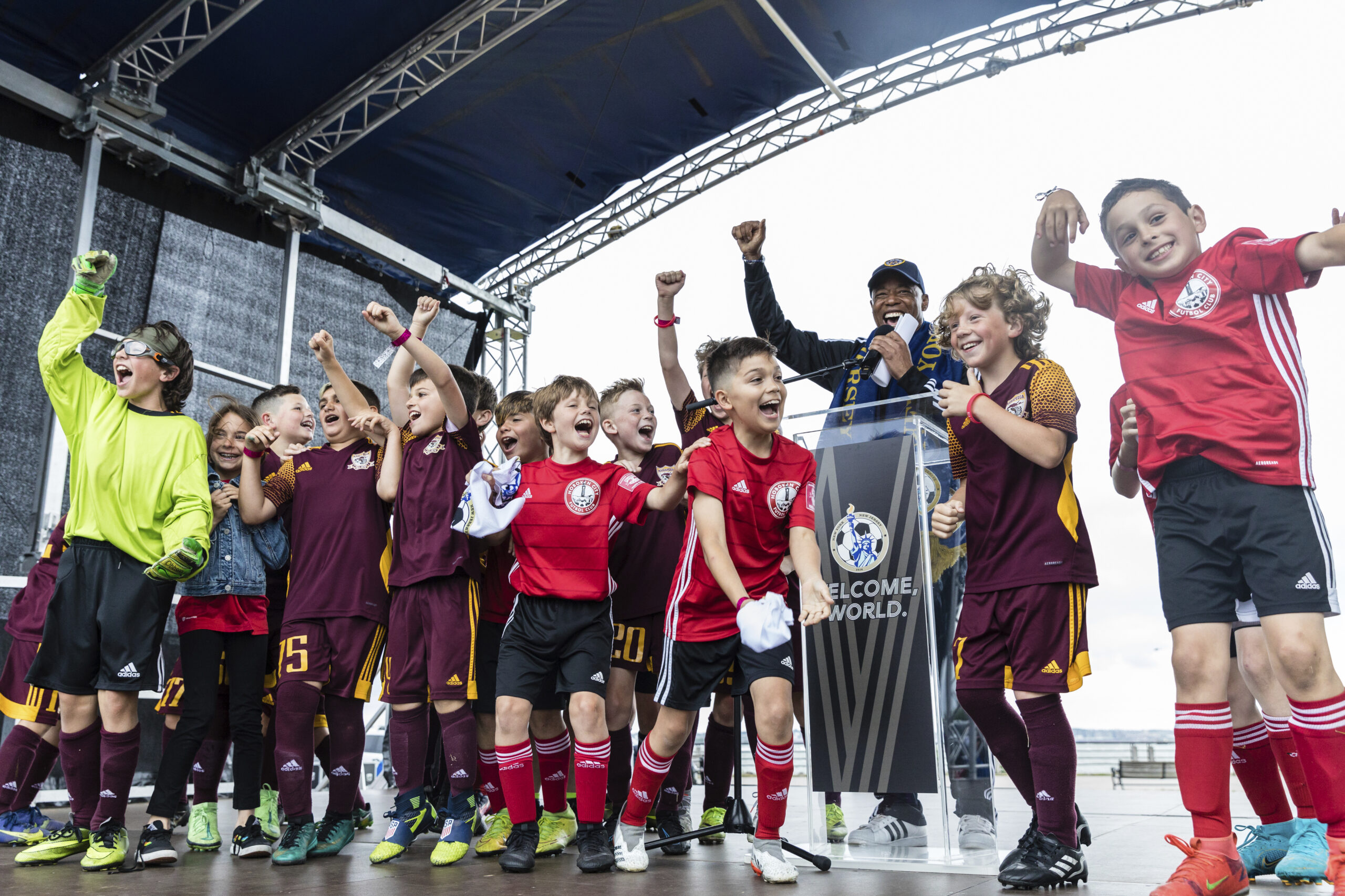 Youth soccer players join New York Mayor Eric Adams on stage during a 2026 FIFA World Cup host city selection watch party at Liberty State Park in Jersey City, N.J., Thursday, Jun. 16, 2022. (AP Photo/Stefan Jeremiah)