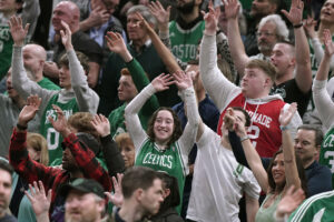 Fans wave their arms while waiting to catch T-shirts during an NBA game between the Brooklyn Nets and the Boston Celtics on March 6, 2022, in Boston. The fans were not required to wear face masks while attending the game at the TD Garden for the first time since the beginning of the COVID-19 pandemic. A mask mandate has not been in effect this season. (AP Photo/Steven Senne)